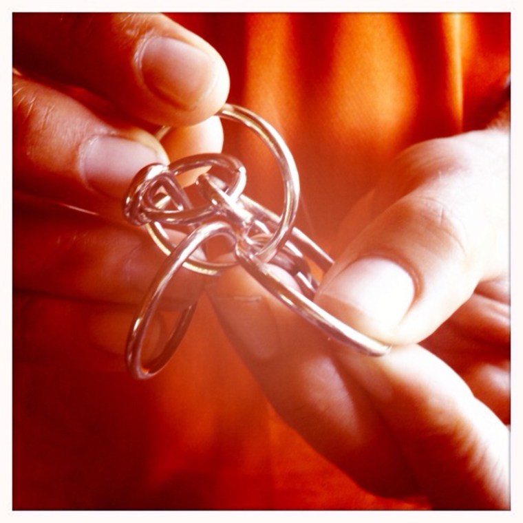 Untangling intricately combined metal shapes - disentanglement puzzles can provide hours of frustrating fun.(© All Rights Reserved)